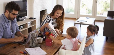 Father-using-laptop-while-mother-playing-with-children